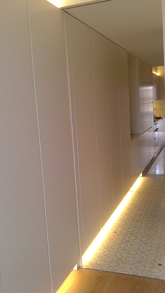 Armario pasillo con puertas practicables lacadas en blanco con uñero. Instalación en Paralelo de Barcelona