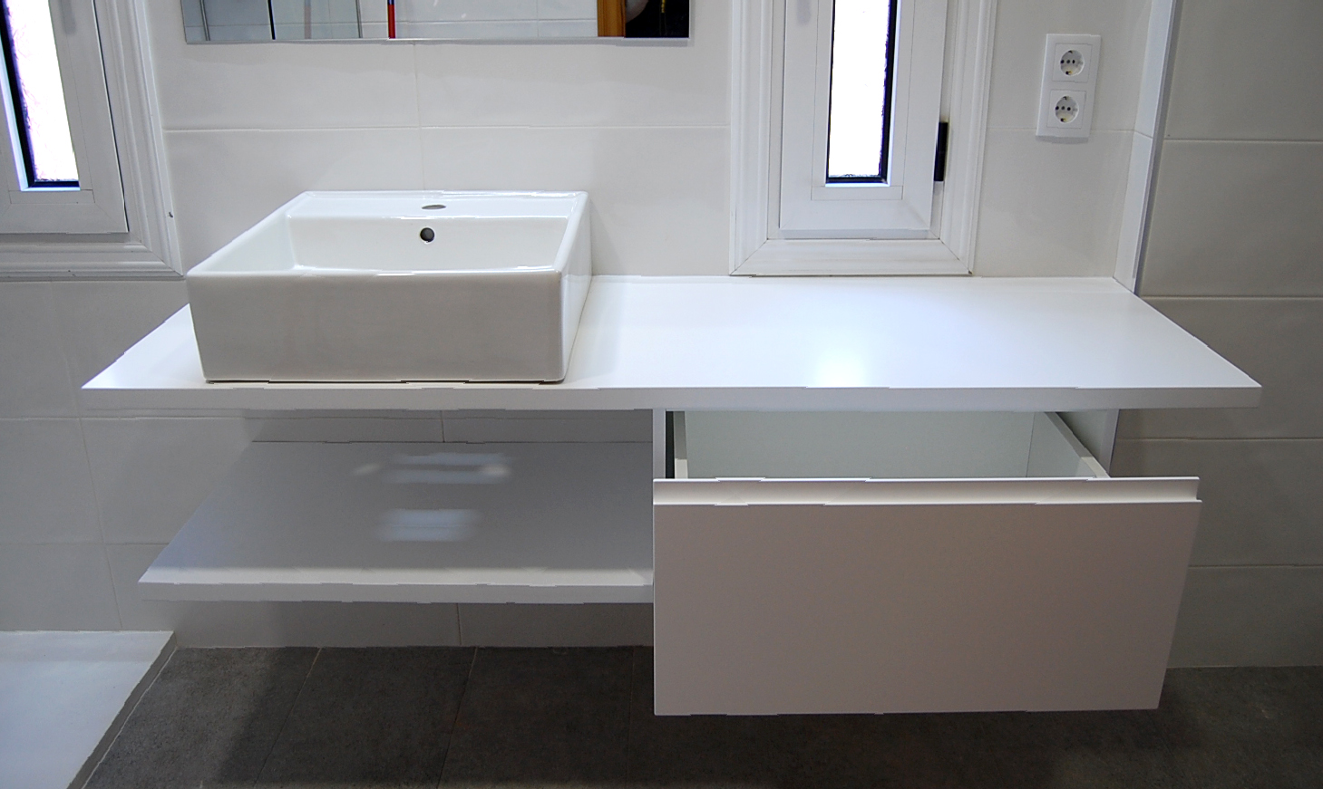 Mueble de baño a medida suspendido lacado blanco satinado con uñero. Encimera hidrófuga, cajón con guía de extracción total con freno y estante.